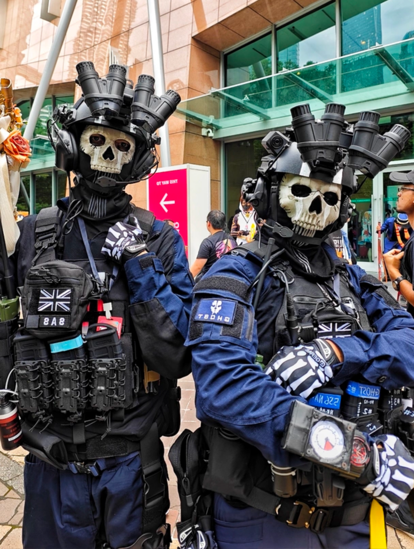 Two cosplayers in full Ghost MW2 operator kit with tactical helmets and skull masks at convention