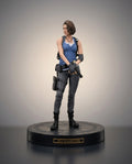 A Jill Valentine collectible figurine from Resident Evil, standing on a black circular base with a gold nameplate. She is depicted wearing her signature blue tank top, gray pants, and black combat boots and gear, set against a neutral gray studio background.