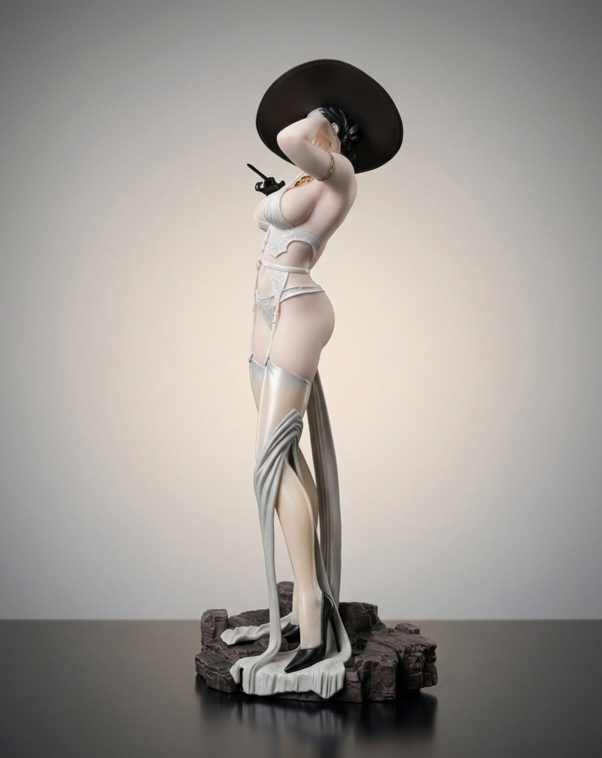 A stylized Lady Dimitrescu figurine in a pale pink and white lingerie outfit with a large black hat, posed on a dark textured base against a neutral studio background.