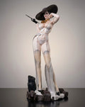 A collectible figurine of a Lady Dimitrescu from Resident Evil  in a white lingerie set with sheer stockings, a large black hat, standing on a dark base against a neutral studio background.