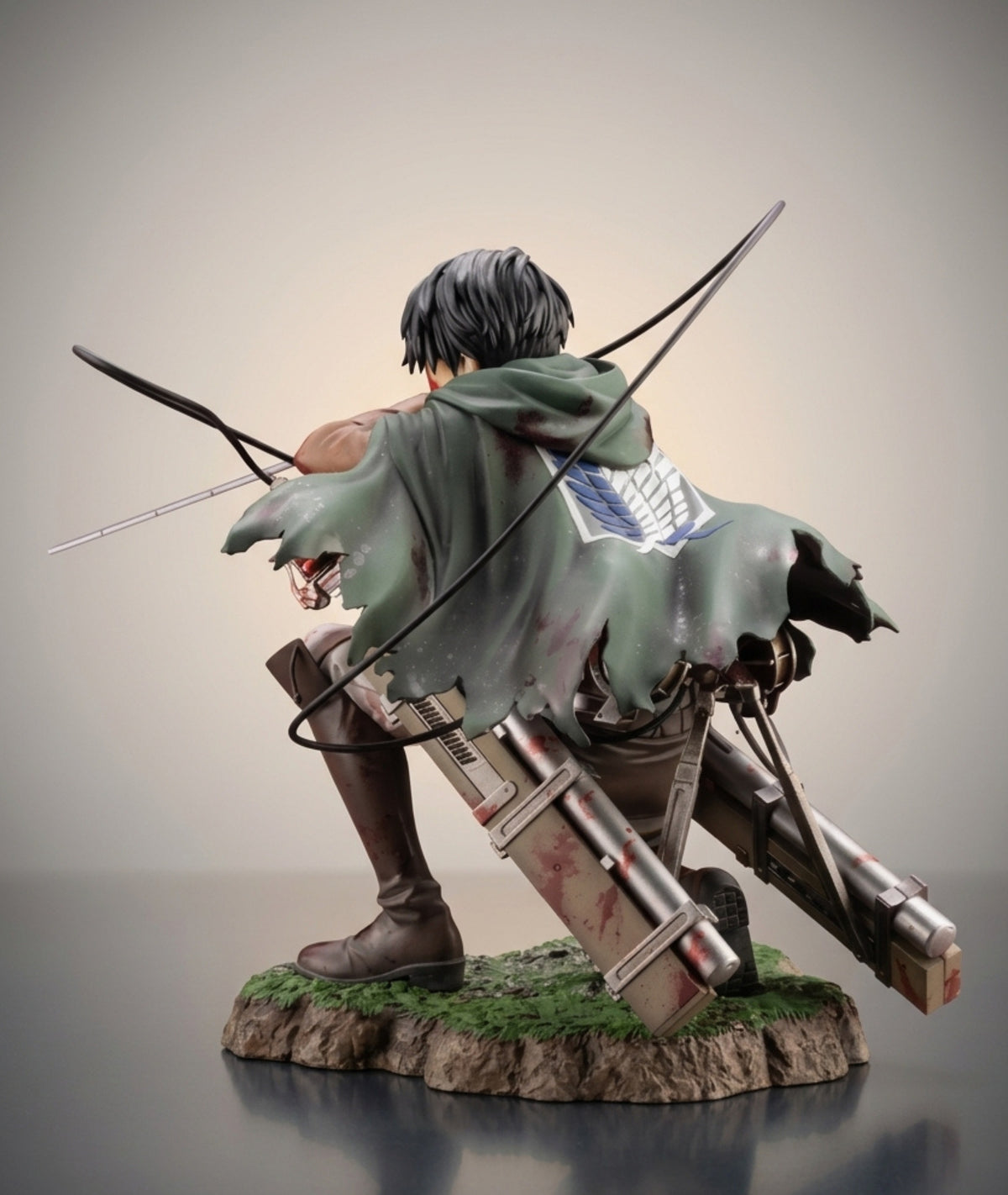 Attack on Titan collectible figurine of Levi Ackerman from behind, crouching with a bow and arrow on a rocky base with green moss.