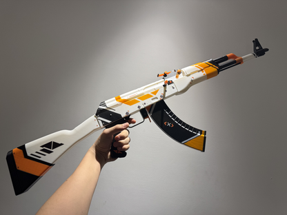 Real life size AK-47 Asiimov CS2 skin replica — white and orange futuristic design detail shot, display stand, studio lighting