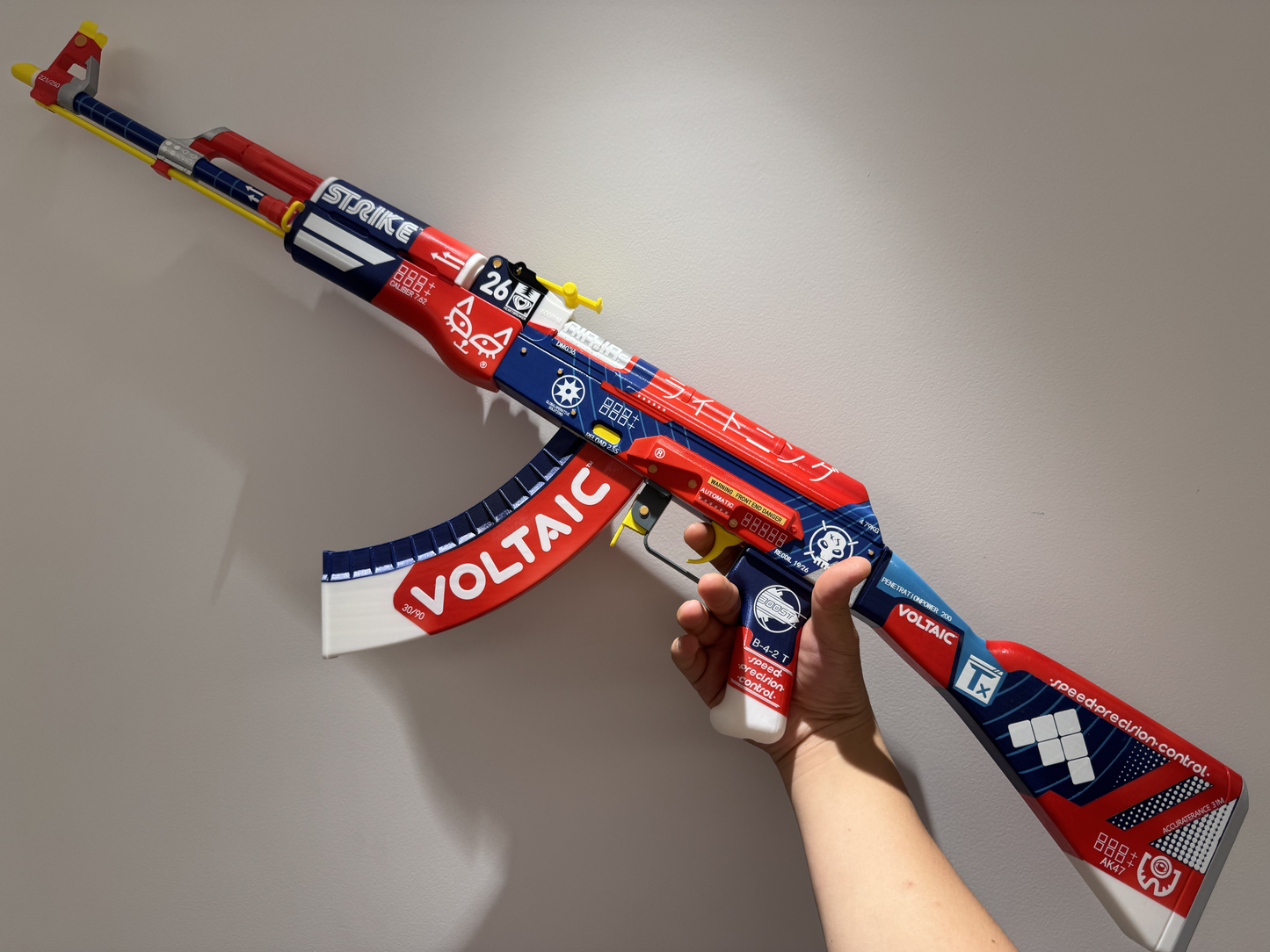 AK-47 Bloodsport CS2 life size replica held from above showing full red blue Voltaic design against white wall