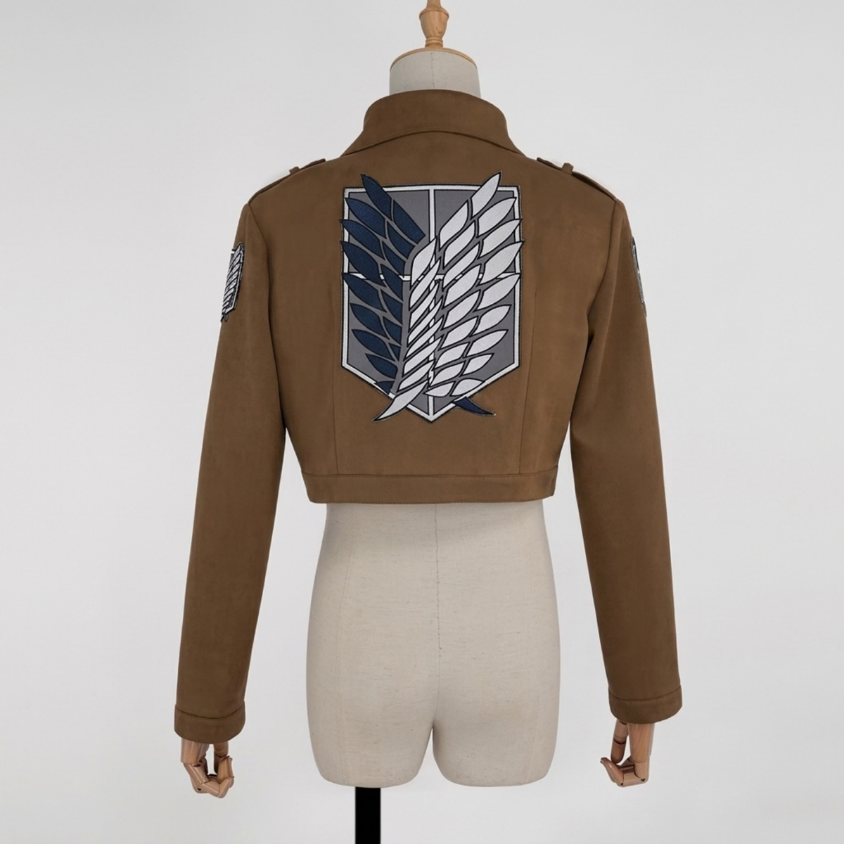 Brown cropped scout jacket cosplay with large wings emblem on the back and sleeve patch, back view on mannequin