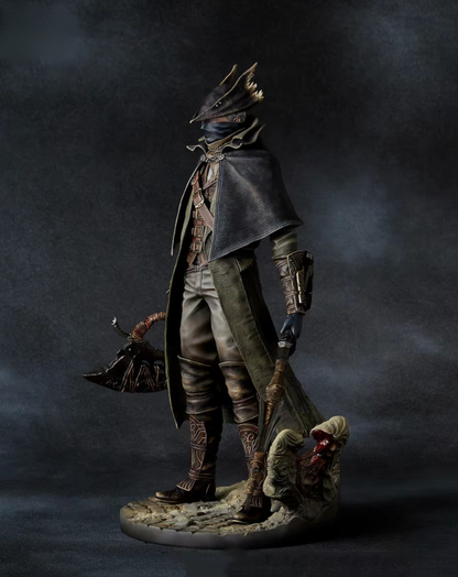 A detailed collectible figurine of a Hunter from Bloodborne dark fantasy character standing on a rocky base, holding a large axe, against a dark smoky studio background.