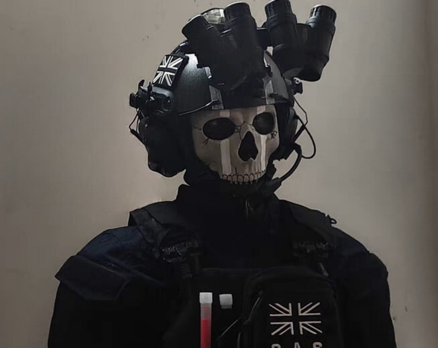 Person wearing Ghost MW2 cosplay full kit — skull balaclava, tactical vest, and gloves at indoor airsoft event
