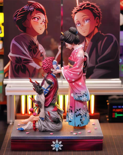 Anime figurine set featuring a kneeling 	Akaza and Koyukiin a red and gray outfit with black hair, and a standing character in a pink and blue kimono, displayed on a base with two large character posters in the background.