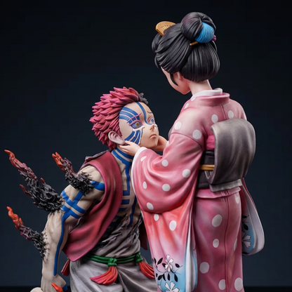 A detailed collectible figurine of two anime characters Akaza With Koyuki, posed dynamically against a dark studio background. Tanjiro is kneeling with his signature pink hair and blue mask visible, while Zenitsu stands from behind wearing a pink polka-dot kimono.