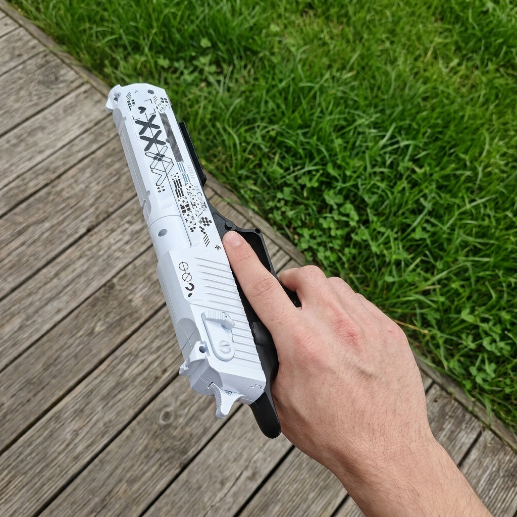 Hand holding Desert Eagle Printstream CS2 replica from above — top down view showing white slide with black XX geometric pattern, wooden deck and grass background, natural daylight
