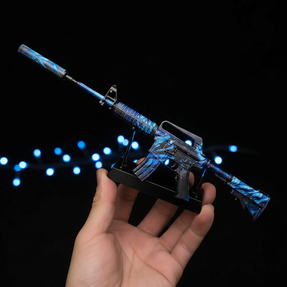 Hand holding Mini M4A1-S Nightmare CS2 skin replica — small metal collectible desk piece, black background, front angle view