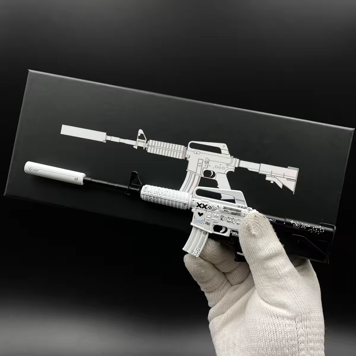 Hand holding Mini M4A1-S Printstream CS2 skin replica — small metal collectible desk piece, black background, front angle view
