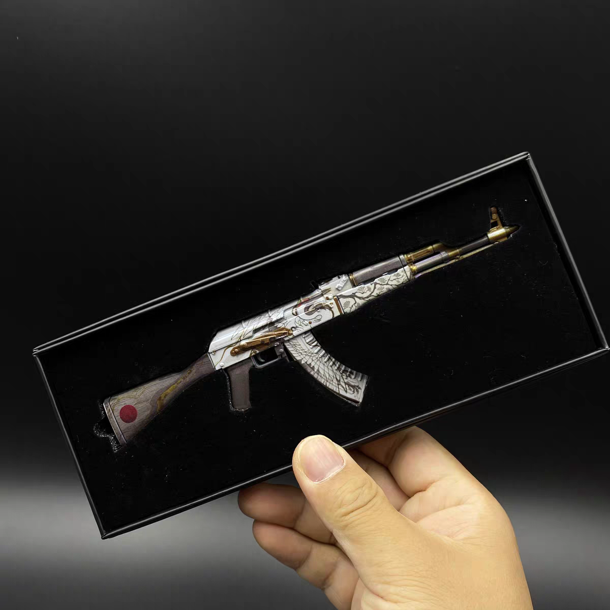 Hand holding CS2 AK47 Crane Flight mini replica in display box, showing white silver base with detailed crane artwork skin
