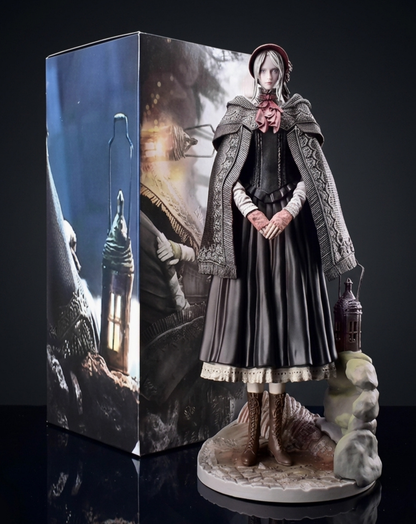 A detailed collectible Doll figurine of from Bloodborne, standing on a stone base next to a matching illustrated display box, set against a dark studio background.