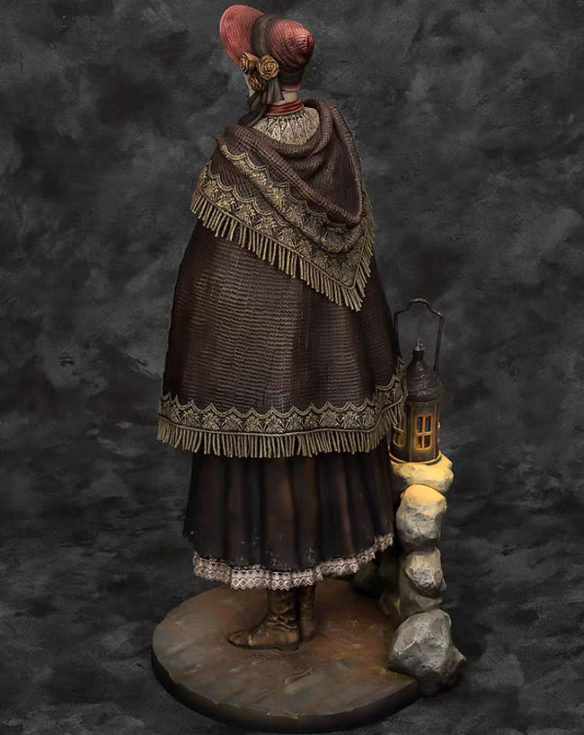 A detailed The Doll Bloodborne figurine of a woman from behind, wearing a dark brown fringed cloak, a red headpiece, and boots, standing on a round base next to a lantern and small rocks against a dark textured backdrop.